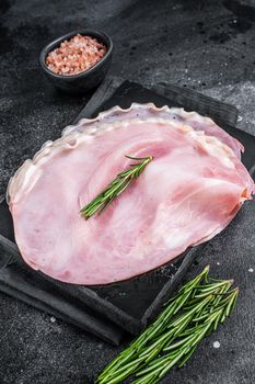 Sliced pork ham on marble board. Black background. Top view.