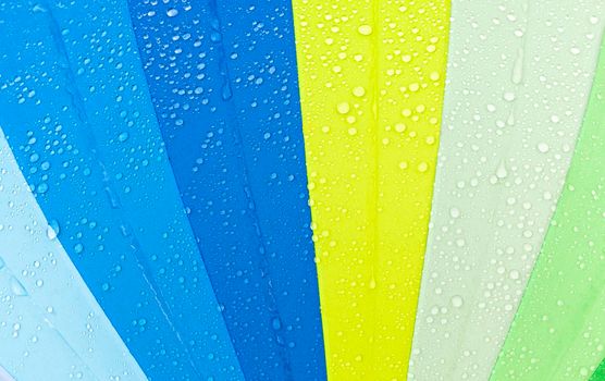 colorful umbrella like a rainbow with drops of water when it rains, closeup in nature
