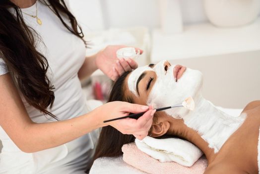 Aesthetics applying a mask to the face of a beautiful woman in modern wellness center. Beauty and Aesthetic concepts.