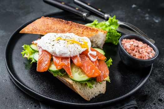 Sandwich toast with Benedict egg, smoked salmon and avocado on bread. Black background. Top view.