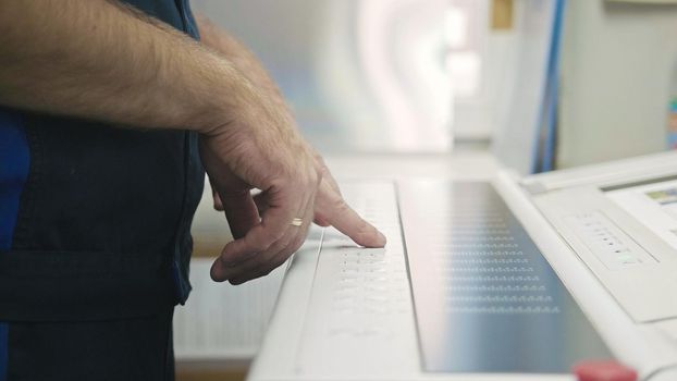 Industrial Worker. Man using industrial control panel of the Printing machine, close up