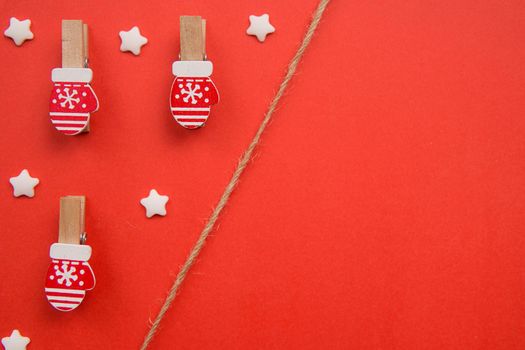 Christmas decorations decorative background. Decorative pins in the form of red gloves on a red background. Top view, minimalism, flat lay. Space for text.