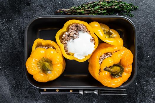 Baked yellow Sweet bell pepper stuffed with beef meat, rice and vegetables. Black background. Top view.
