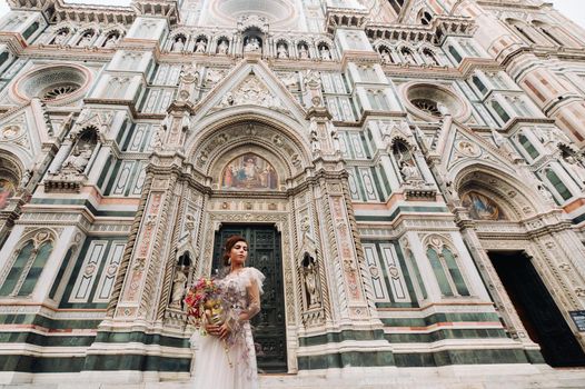 the girl-bride is with beautiful flower pattern as a mask in Florence, stylish bride in a wedding dress standing with a mask in the Old town of Florence. Model girl in Florence.