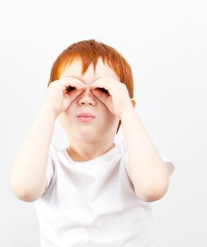 red-haired five-year-old child who made glasses during the game, on a gray background, not isolated