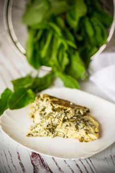 fried egg omelet with spring sorrel inside, on a wooden table.