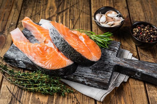 Raw Salmon steaks on a wooden cutting board with thyme and rosemary. wooden background. Top view.