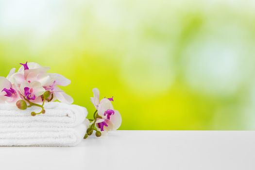 Towels with flowers on light table against blurred background, front view
