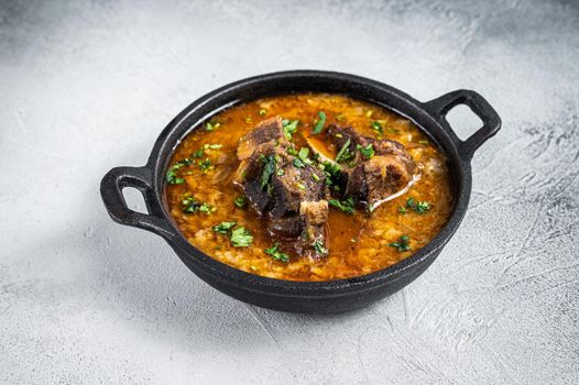 Kharcho soup with beef meat, rice, tomatoes and spices in a pan. White background. Top view.