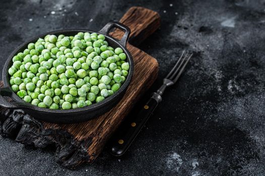 Fresh Frozen green peas in a pan. Black background. Top view. Copy space.