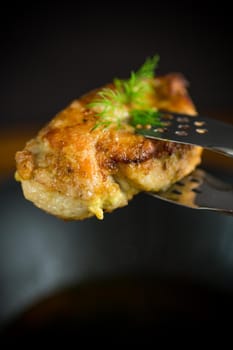 a piece of fried chicken fillet with spices on a black background