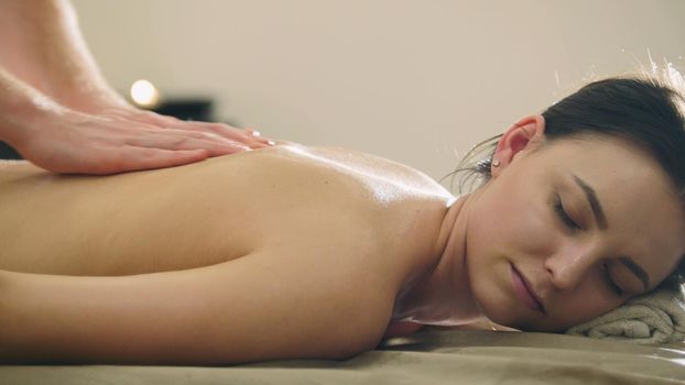 Man's hands on the back of the girl in massage parlor , close up