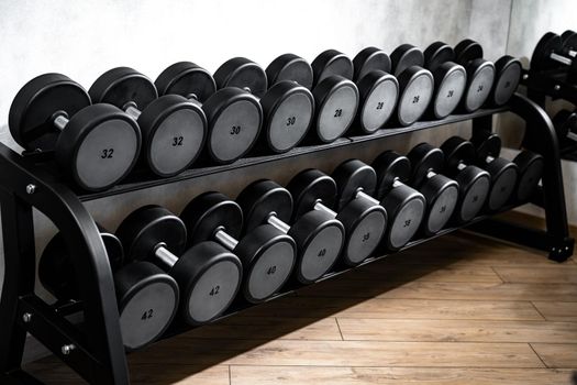 Rows of metal dumbbells on rack for bodybuilding in a gym