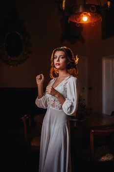 a bride in underwear and a white robe in the interior of a Villa in Italy at a wedding.morning of the bride in Tuscany.boudoir photo session at the Villa