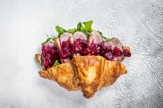 Duck breast Croissant sandwich with steak slices, arugula and sauce. White background. Top View.