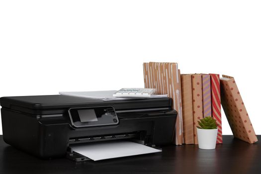 Office table with laser printer and books against white background, close up