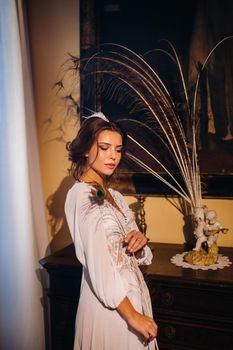 a bride in underwear and a white robe in the interior of a Villa in Italy at a wedding.morning of the bride in Tuscany.boudoir photo session at the Villa