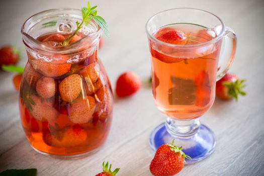 Sweet refreshing berry compote of ripe strawberries in a decanter on a wooden table