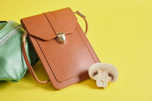 brown and green eco leather bags and champignons on a yellow background, vegan leather from mushroom mycelium concept