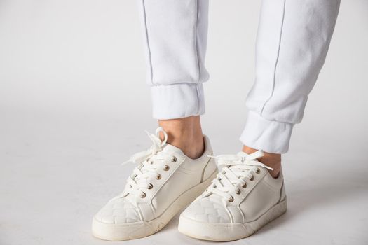 Fashionable women's white leather sneakers. Stylish men's shoes. Casual design. Close-up of male legs.