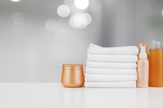 Spa still life with towels and skincare cosmetics against blurred background, close up