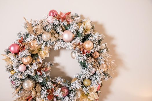 Christmas wreath made of natural fir branches hanging on a white wall. Wreath with natural ornaments: bumps, walnuts, cinnamon, cones.