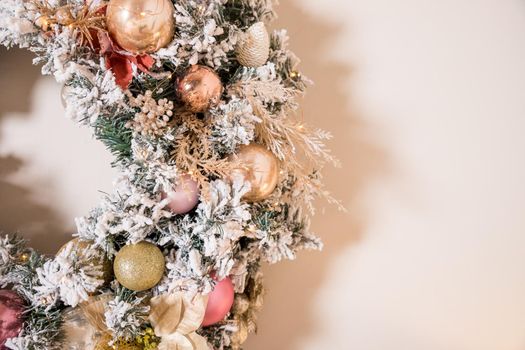 Christmas wreath made of natural fir branches hanging on a white wall. Wreath with natural ornaments: bumps, walnuts, cinnamon, cones.