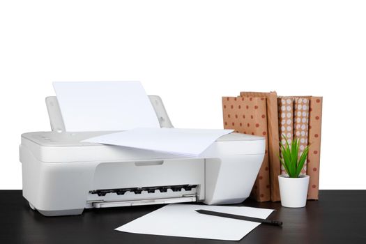 Printer and stack of books on black table against white background, close up