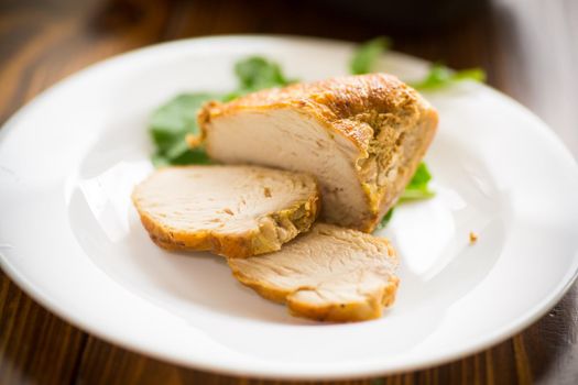 baked chicken fillet pieces with spices and herbs, in a plate on a wooden table