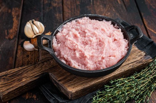 Uncooked Raw minced chicken and turkey meat in a pan with herbs. Dark wooden background. Top view.