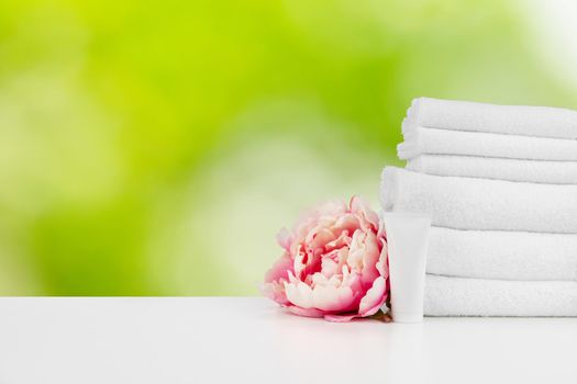 Spa still life with towels and skincare cosmetics against blurred background, close up