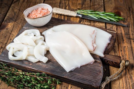 Sliced rings Raw Calamari or Squid on a wooden board with rosemary. wooden background. Top view.