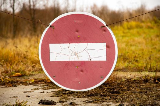 old rusty no entry sign on an old abandoned road in a field. close up