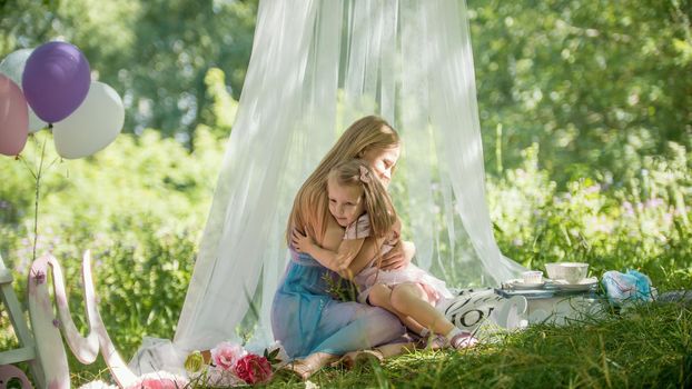 Mother and daughter is hugging in park - picnic and birthday, telephoto view