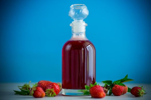 sweet cooked strawberry syrup in a glass decanter on a wooden table