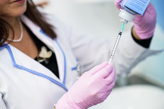 Aesthetic doctor preparing the syringe with the botox to be injected in her patient.