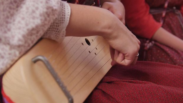 Gusli - woman in Russian folk costume playing vintage musical instrument , close up