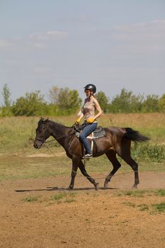 Women is horse riding - red hair girl in summer meadow, telephoto