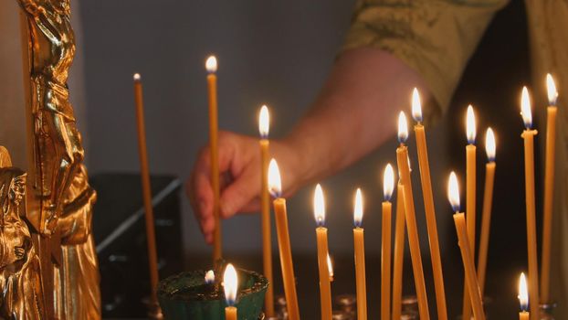 The parishioner put a candle inside an Orthodox church, close up