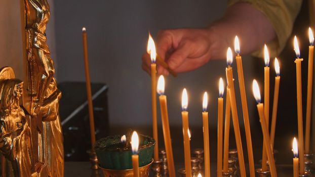 The parishioner put a candle inside an Orthodox church, close up