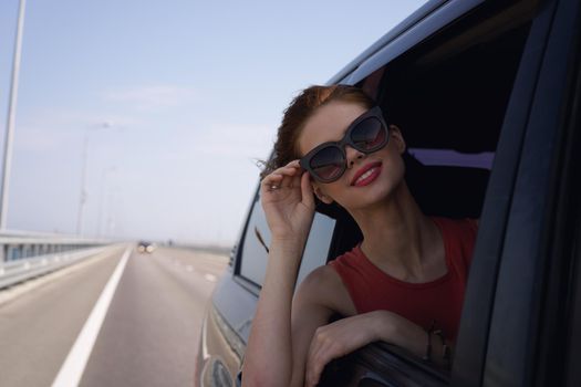 a woman is driving in a car on the road and looking out of the window. High quality photo