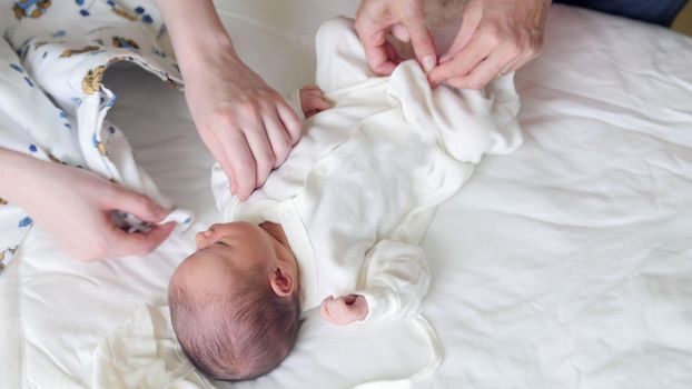 Newborn baby, mother and nurse - swaddling the infant, close up