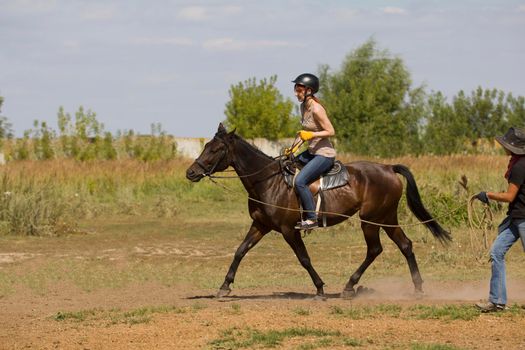 Horseback riding lessons - young woman riding a horse, telephoto shot