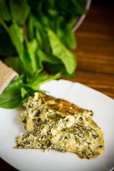 fried egg omelet with spring sorrel inside, on a wooden table.