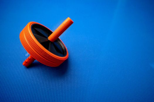 Abs roll out exercise fitness wheel on blue background, close up