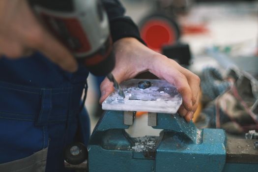 Man working drill plexiglass in vise - workshop, close up