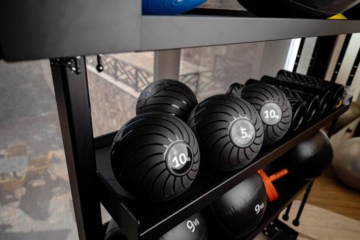 Balls and foam roller sport equipment in a gym on shelf
