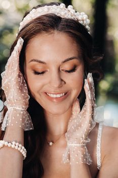 An elegant bride in a white dress, gloves with a bouquet on a waterfall in the Park, enjoying nature.Model in a wedding dress and gloves in the forest.Belarus.