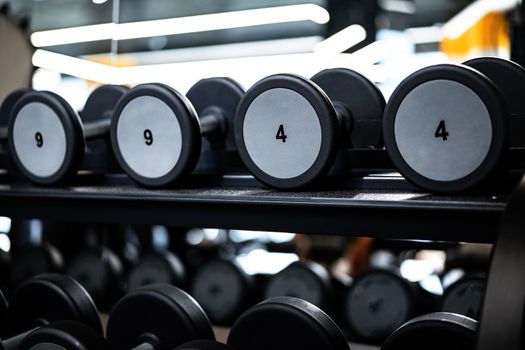 Close up photo of new dumbbells on a rack in a gym