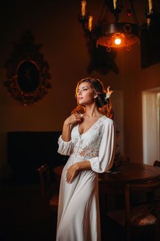 a bride in underwear and a white robe in the interior of a Villa in Italy at a wedding.morning of the bride in Tuscany.boudoir photo session at the Villa
